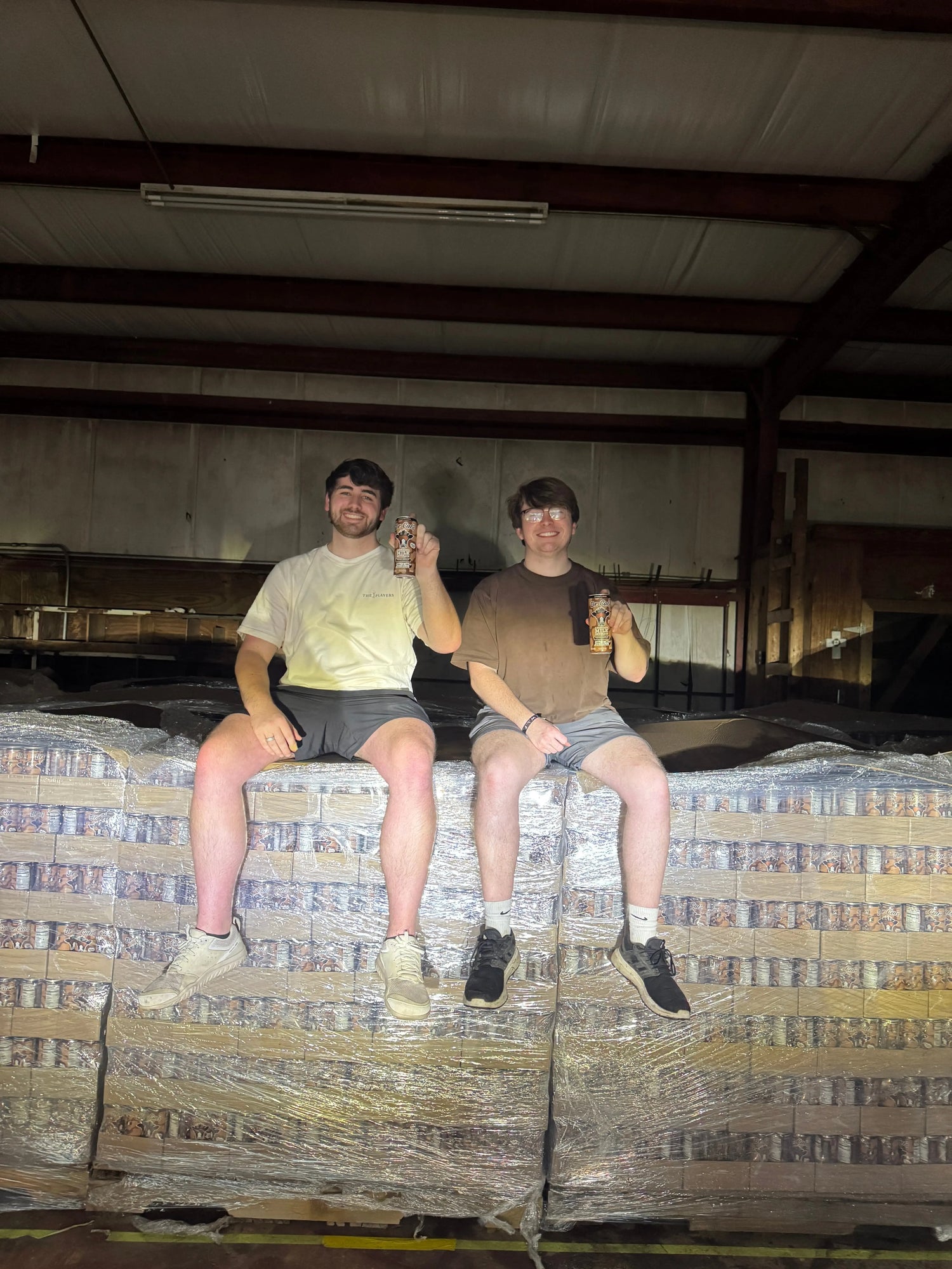 Two people sitting on a stack of pallets of Dr. Cal's Energized Milk Beverage